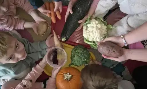 Dłonie uczniów, na których są różne warzywa.