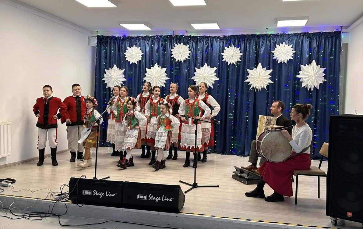 Uczniowie w strojach kurpiowskich występują na scenie.