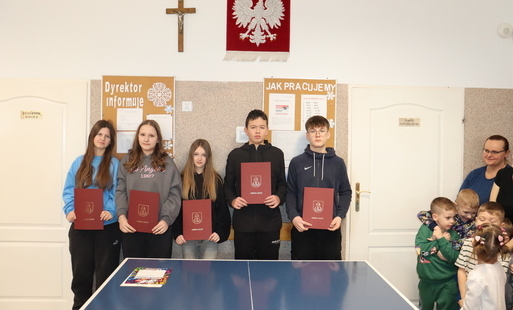 Uczniowie trzymający w rękach Edukacyjne Nagrody Wójta.